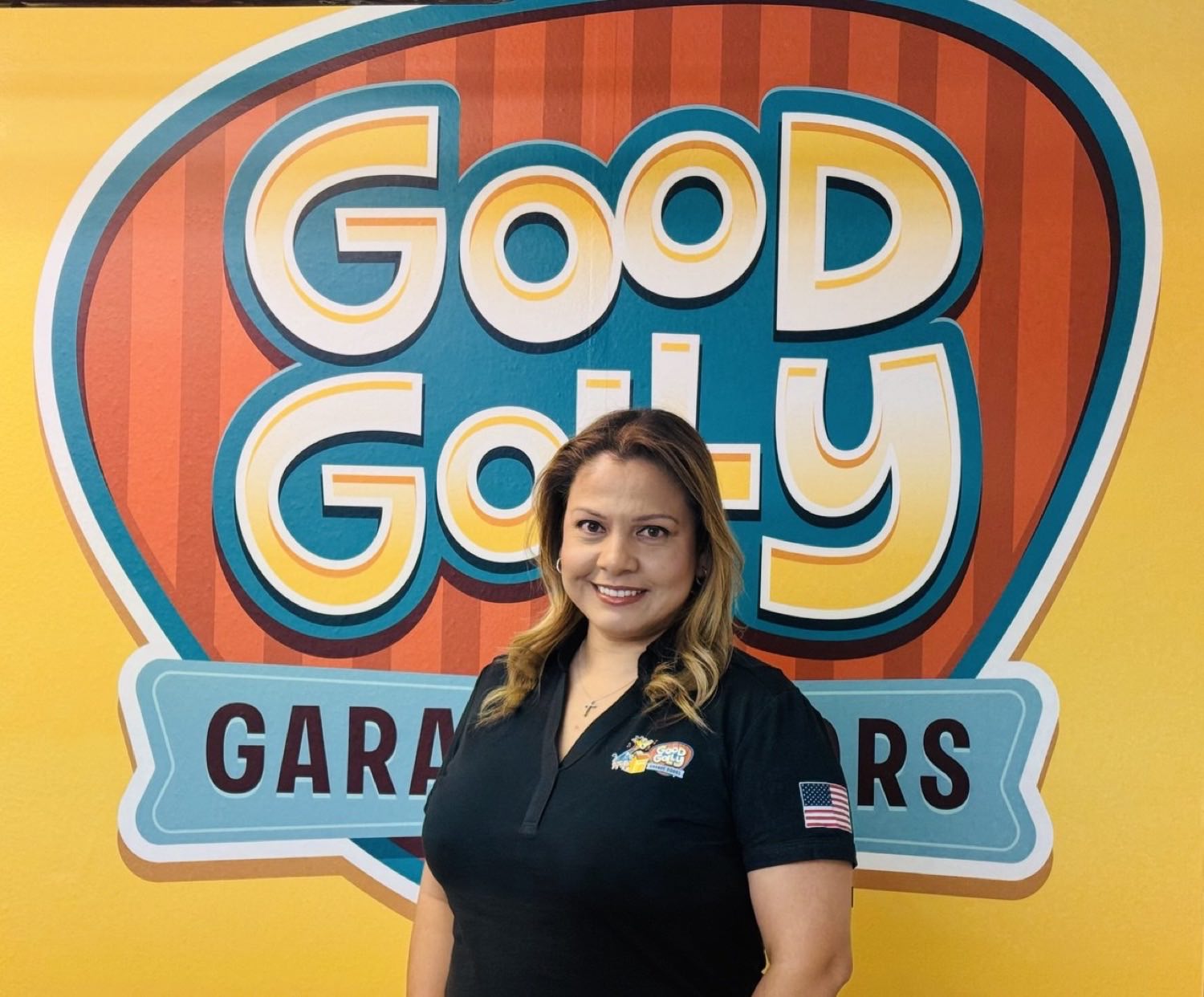 Reyna Kline in a Good Golly Garage Doors shirt in front of the painted Good Golly sign at the Las Vegas shop