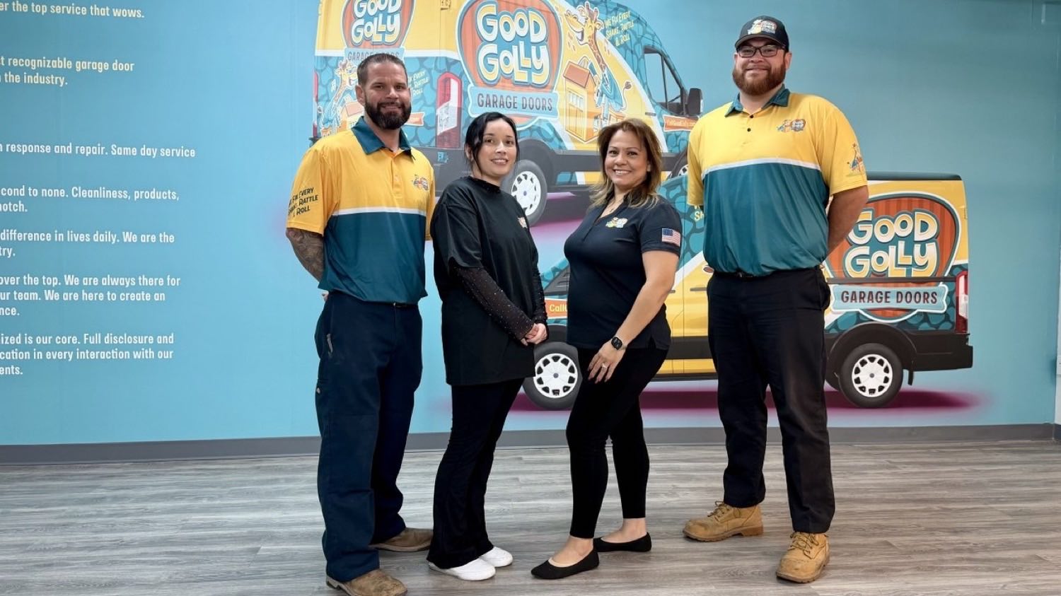 Four of the Good Golly Garage Doors Las Vegas team in branded shirts in front of the painted van mural at their shop