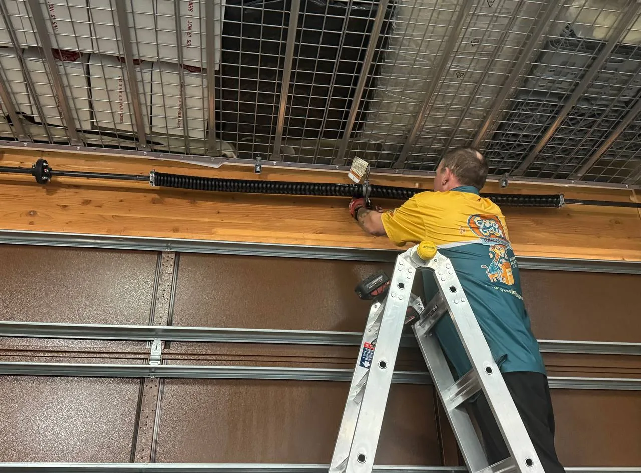 Las Vegas residential garage door technician servicing torsion springs from a ladder