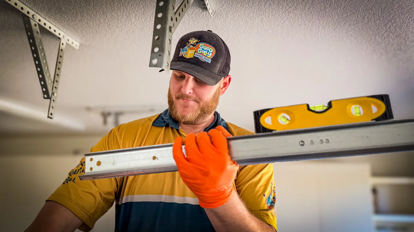 Las Vegas residential garage door technician checking track alignment with a level