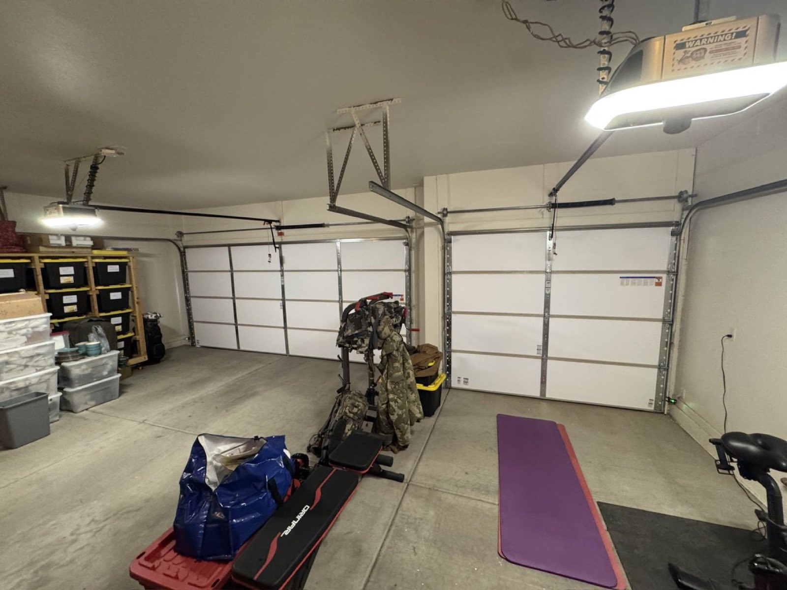 Two white sectional garage doors and their overhead openers seen from inside a two-bay Phoenix garage