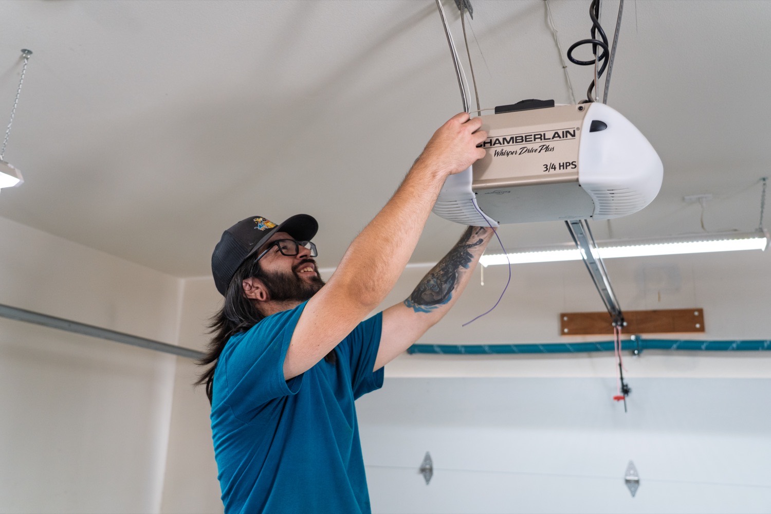 A Good Golly technician fitting a Chamberlain belt-drive opener to the ceiling of a Victorville garage
