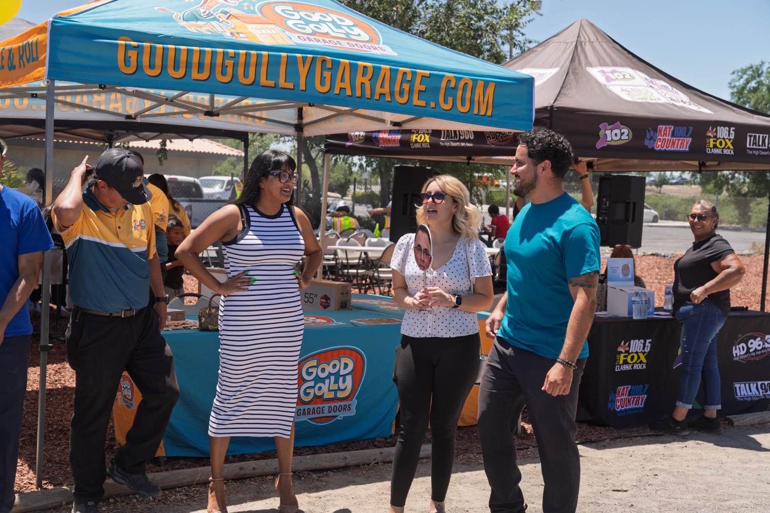The Good Golly Garage Doors booth at a High Desert community event, staff talking with visitors under the branded canopy