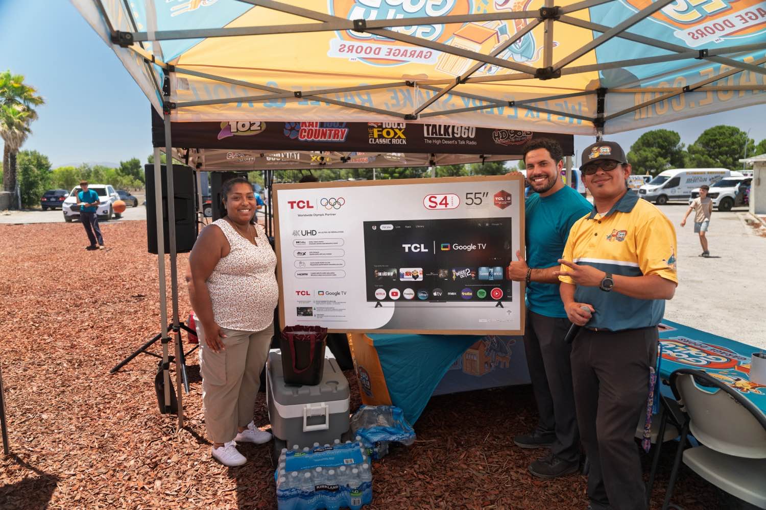 Good Golly Garage Doors staff handing a television to a prize winner at a High Desert community event