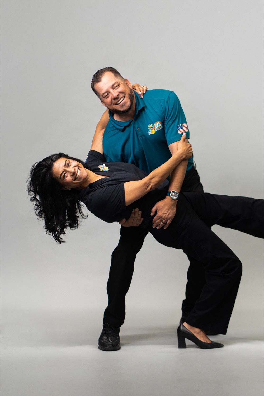 Joey Cisneros dipping Genoveva Cisneros, the Good Golly Garage Doors Victorville owners, laughing in a studio portrait