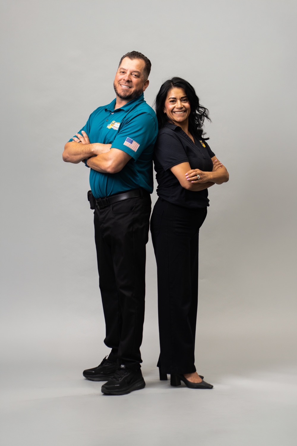Joey and Genoveva Cisneros, owners of the Good Golly Garage Doors Victorville location, standing back to back in a studio portrait