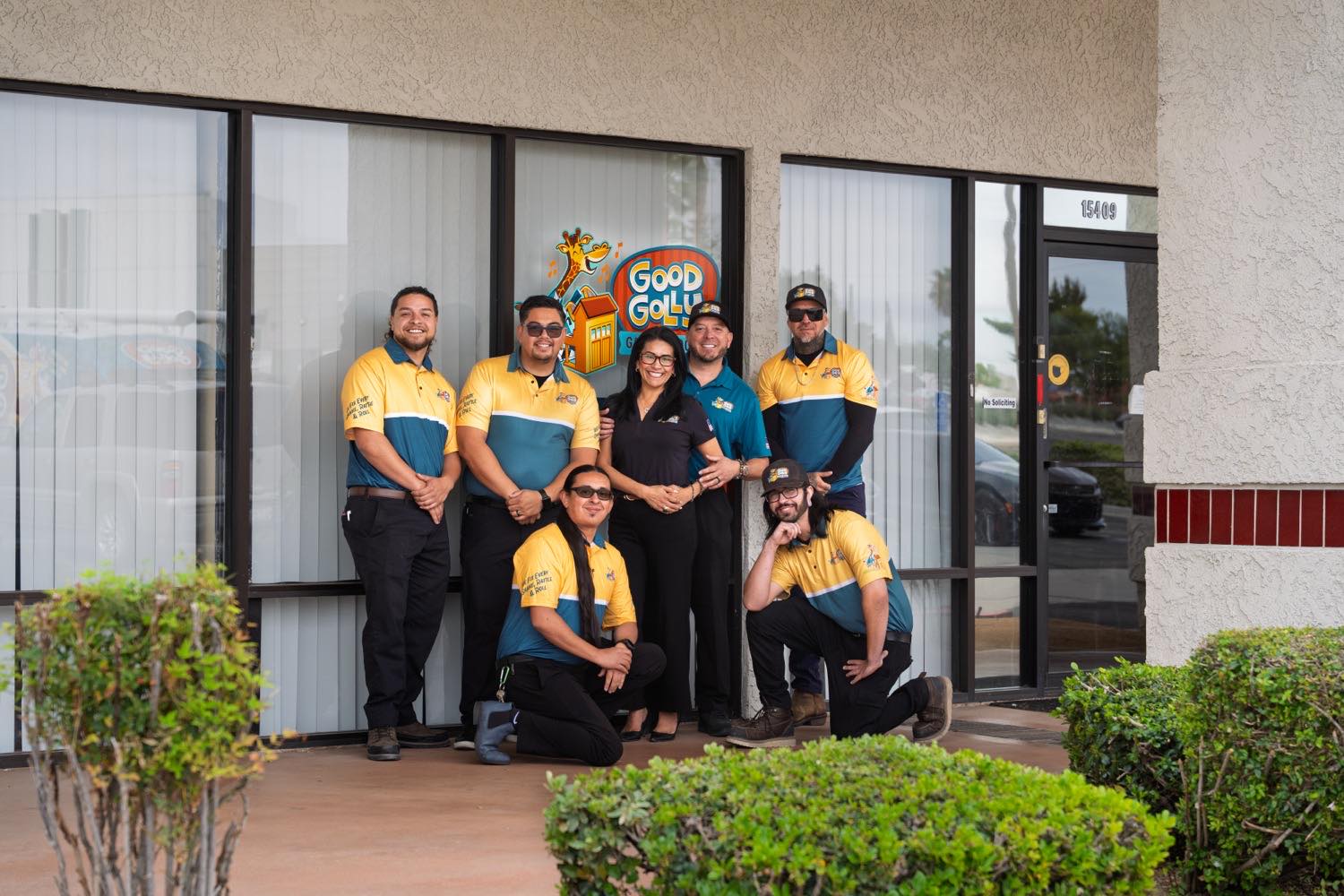 The Good Golly Garage Doors Victorville crew of seven outside their shop, under the Good Golly sign