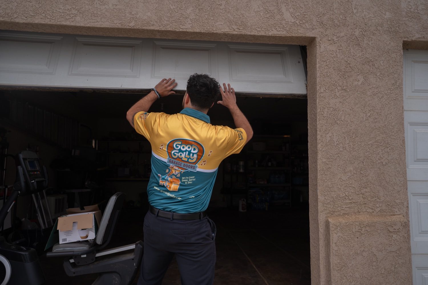 A Good Golly technician lifting a garage door by hand to test its balance at a Victorville home
