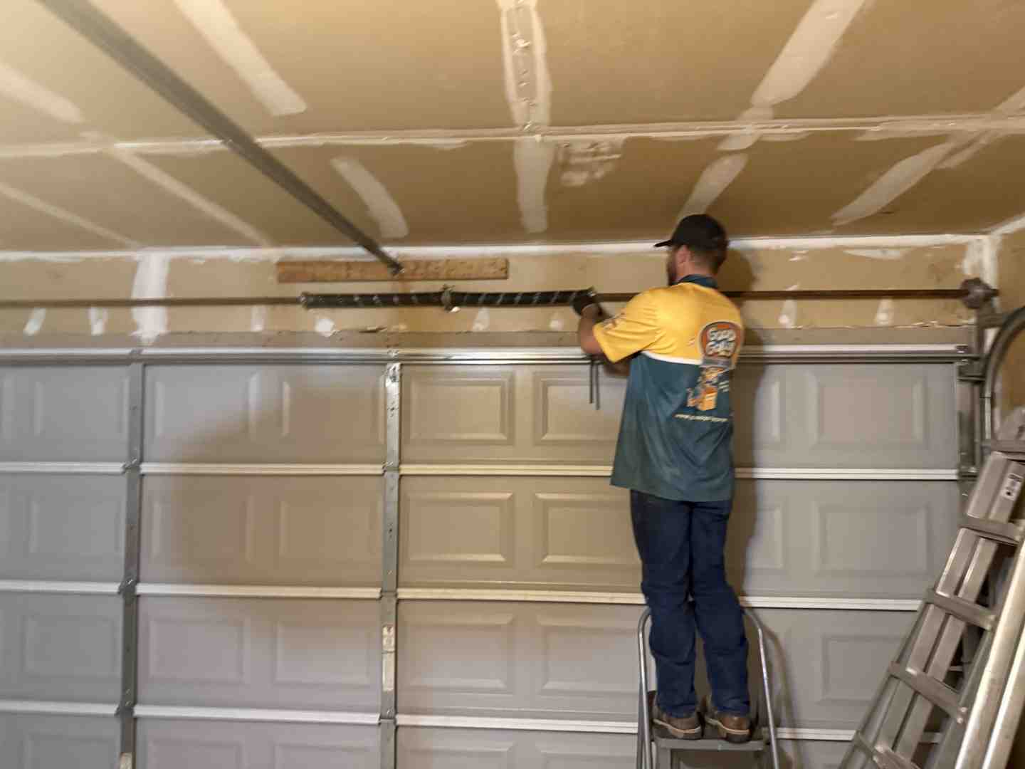 professional garage door technician using solid steel winding bars to safely balance a torsion spring professional garage door technician using solid steel winding bars to safely balance a torsion spring