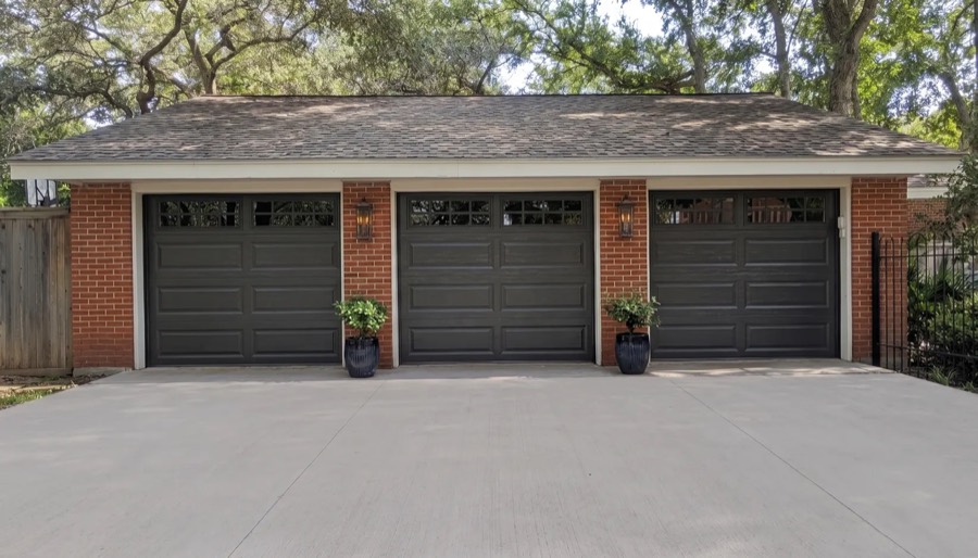 Three Clopay Classic Steel long-panel garage doors in iron ore on a brick home