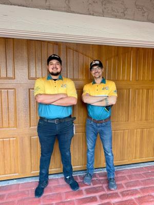 Technicians in front of a newly hung woodgrain garage door in Las Vegas