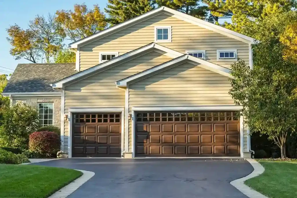 A large beige house with two brown garage doors, each with gridded windows along the top.
