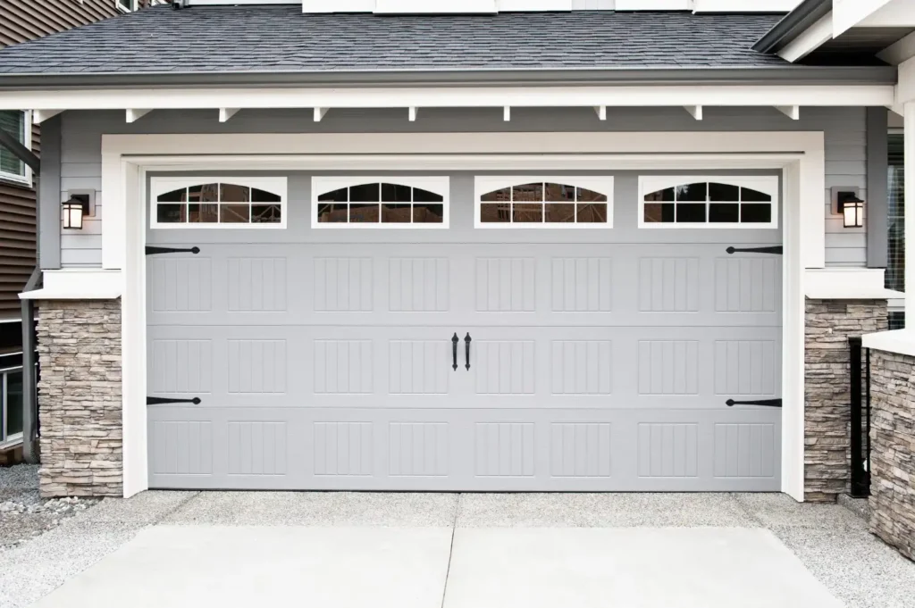 Exterior view of a closed white sectional garage door installed on a building with industrial metal siding.