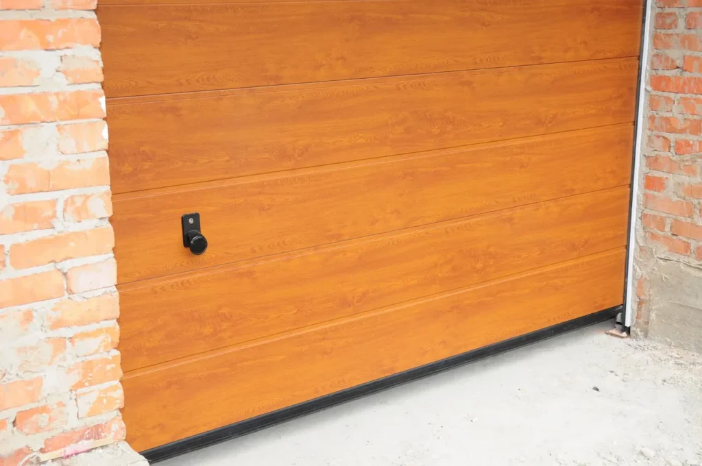Close-up of wooden garage door with horizontal panels, black handle, and brick wall framing.