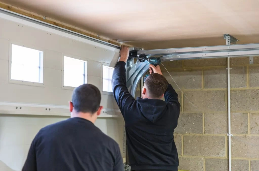 Two men installing garage door tracks.