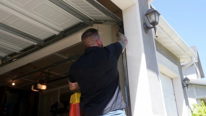 Technician repairing outdoor garage door track.